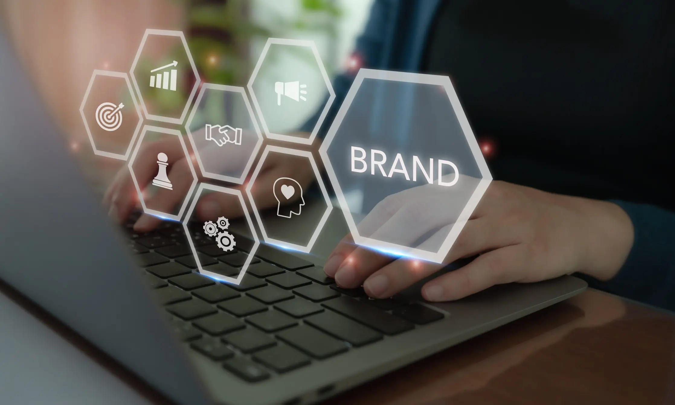 Person interacting with digital brand icons on a laptop keyboard.